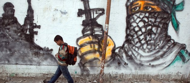 Palestinian boy passing by a grafitti as he walks to school at Jabalia area, northern Gaza Strip