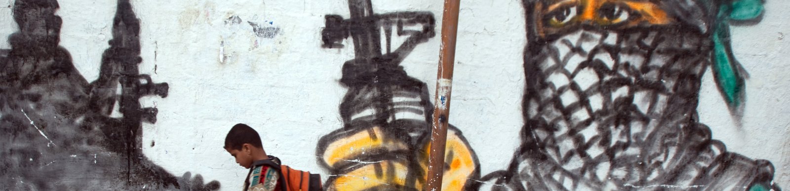 Palestinian boy passing by a grafitti as he walks to school at Jabalia area, northern Gaza Strip