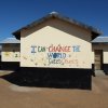 Image of school building against blue sky with colourful handprints and painted letters reading 'I can change the world every child counts'